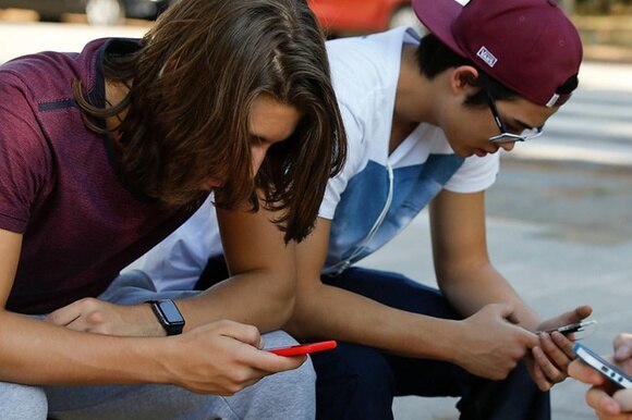 tre giovani seduti intenti ad utilizzare i loro smartphone