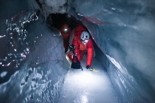 In uno stretto spazio ghiacciato, un uomo con la macchina fotografica si muove quattro zampe