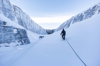 Un uomo cammina attraverso il canale innevato nel ghiacciaio