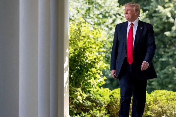 Il presidente americano Donald Trump mentre cammina sorridendo.