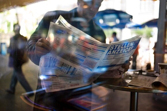 Immagine di un uomo che consulta annunci di posti di lavoro vacanti su un giornale.