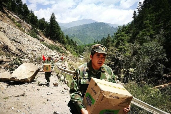 Un soccorritore porta a piedi, verso le zone colpite dal terremoto in Cina, beni di prima necessità.