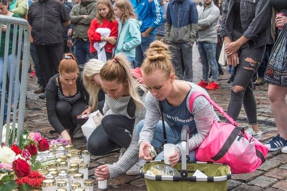 Ragazze posano un lumino nel luogo del multiplo accoltellamento di venerdì a Turku, Finlandia.
