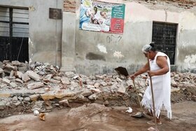 Una mujer intenta limpiar los escombros tras el terremoto.