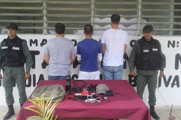 I tre giornalisti, di schiena, insieme a due agenti della Guardia Nacional Bolivariana