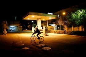 Giovani in bicicletta il mattino presto davanti a una stazione di servizio.