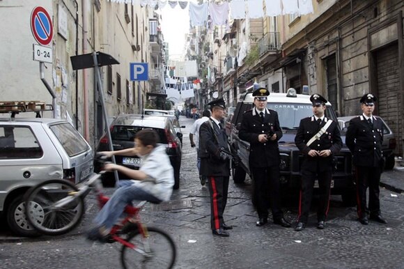 pattuglia di carabinieri a Napoli, con in primo piano un bambino in bicicletta
