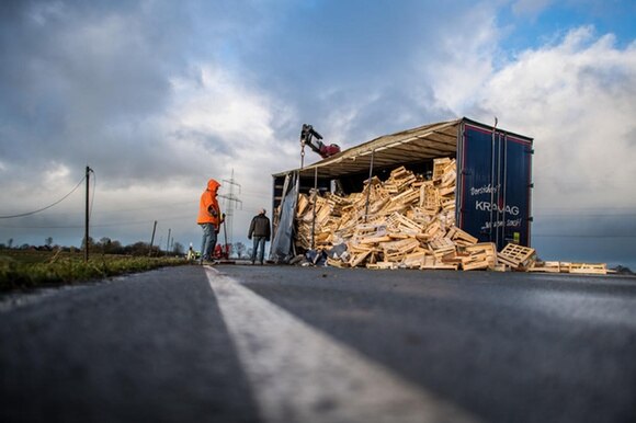 Camion con telone divelto dal vento e contenuto (cassette di legno) riversato su una strada del Nord Reno-Westfalia