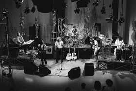 Eugenio Finardi e il suo gruppo sul palco dello studio di Musicalmente. In basso qualche testa del pubblico.