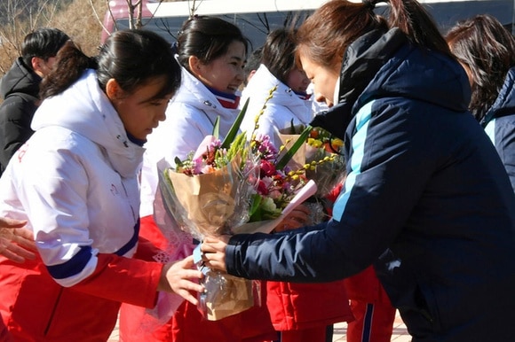 Giocatrici nordcoreane di hockey su ghiaccio ricevono un mazzo di fiori da compagne sudcoreane.