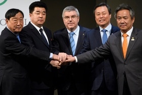 Stretta di mano a 5: due rappresentanti sudcoreani, due nordcoreani e il presidente del CIO in posa davanti ai fotografi.
