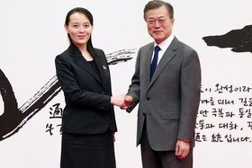 Kim Yo-jong e Moon Jae-in si stringono la mano. Sullo sfondo, un illustrazione con caratteri coreani