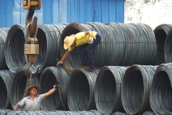 Immagine di lavoratori asiatici che manovrano una gru per spostare delle bobine di cavi d acciaio