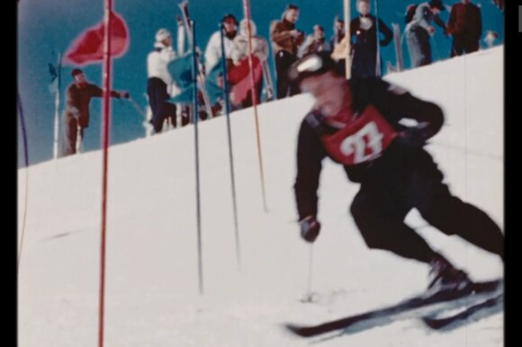 Dai filmati inediti di St. Moritz 48, uno sciatore affronta uno slalom (in primo piano), pubblico (sullo sfondo)