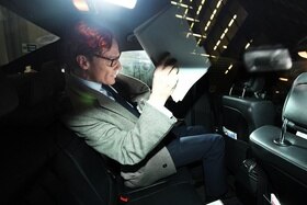 Un uomo (Alexander Nix di Cambridge Analytica) sfoglia un fascicolo sul sedile posteriore di un auto.