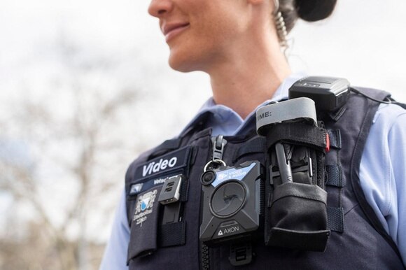 Primo piano del petto di un agente di polizia con giubbino, pila, telecamera bobycam e altri strumenti