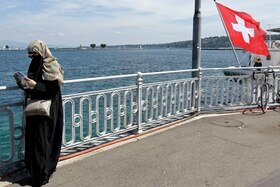 Donna con niqab, nei pressi del lago, consulta una mappa o guida di Ginevra