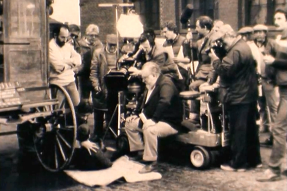 Sergio Leone e il suo cineoperatore filmano una scena che si svolge sul fondo stradale accanto alla ruota di un carro