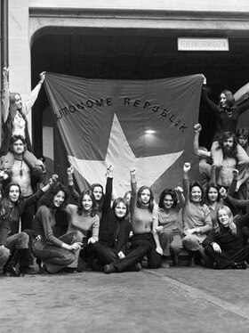 Dei giovani davanti a una grande bandiera della Repubblica autonoma.