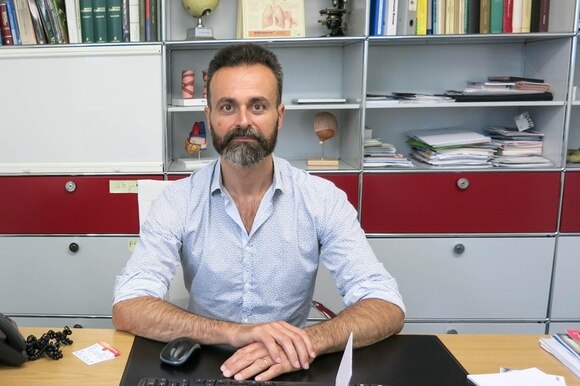 Il medico Massimiliano La Fauci nel suo studio, seduto davanti alla scrivania.