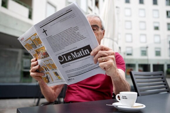 Un lettore seduto al bar con l ultima edizione del giornale Le Matin