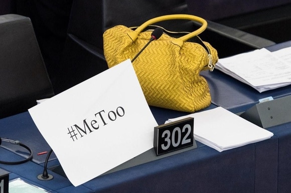 Eine gelbe Handtasche liegt auf einem Pult neben einem Papier, auf dem #MeToo steht.