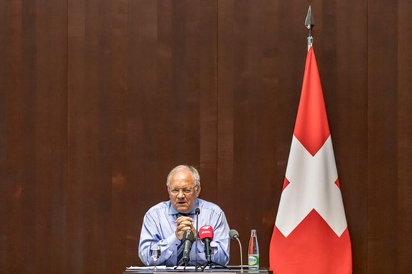 Schneider-Ammann durante la conferenza stampa accanto a una bandiera svizzhera