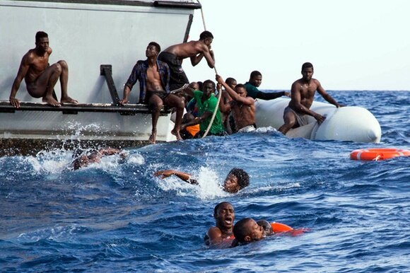 Un operazione di salvataggio di migranti scappatati dalla Libia: si vedono diverse persone cadute in mare