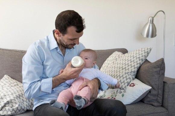 Ein Vater gibt seinem Säugling die Milchflasche.