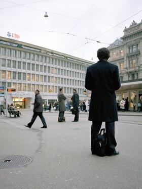Uomo con paltò di spalle su una piazza a Zurigo