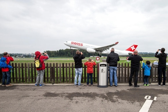 curiosi assistiono al decollo di un aereo della Swiss