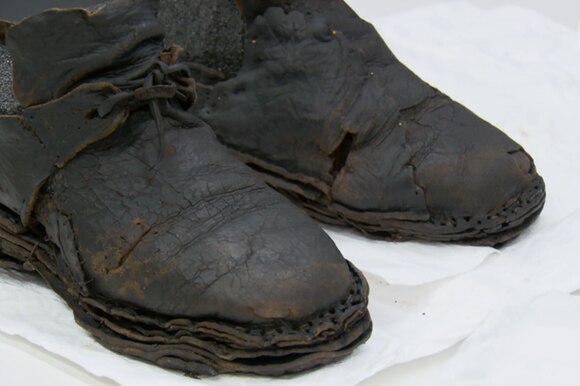 Primo piano di scarponi rovinati dal tempo; dalla foggia si intuisce che appartengono a un altra epoca