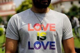 Primo piano del busto di un uomo che indossa una maglietta con la scritta Love is love
