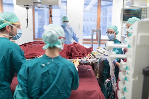 Situazione di sala operatoria con chirurgo e operatori in tuta turchese e con cuffia e mascherina