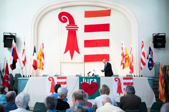 La bandiera giurassiana appesa dietro a un palco di un incontro del Movimento auntonomista giurassiano