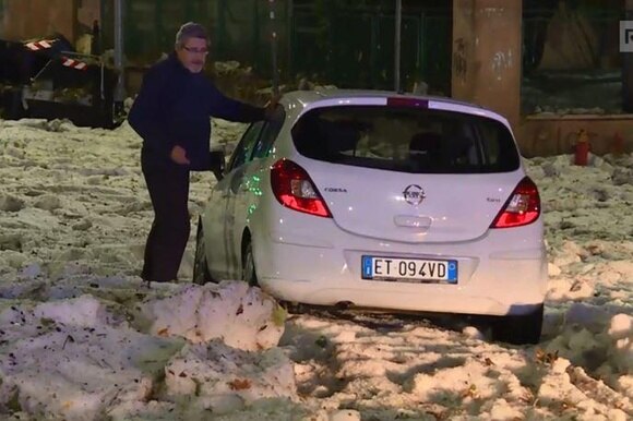 Una macchina bloccata dalla grandine che sembra neve sulle strade di Roma