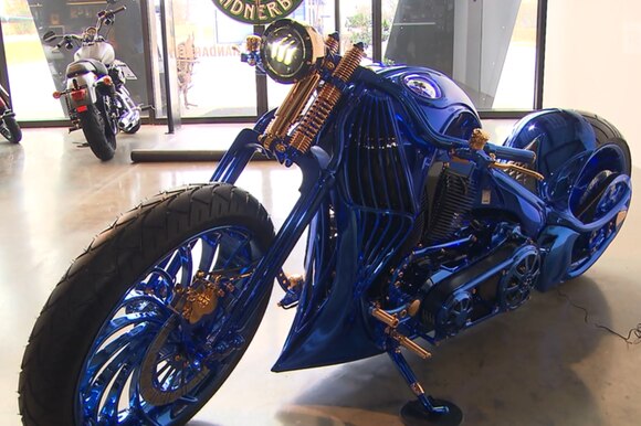 La moto protagonista del servizio (un Harley completamente blu con dettagli placcati oro) parcheggiata in obliquo