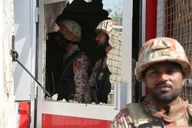 Due militari di profilo intravisti dal vetro rotto di una porta finestra; fuori dall edificio, un terzo militare, sfocato