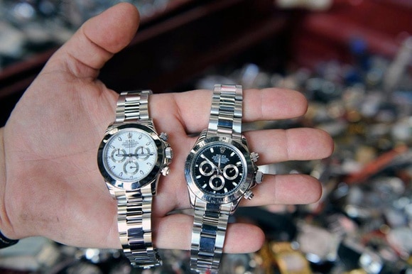 Nella mano di un uomo due orologi Rolex falsi.