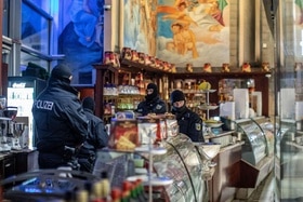 4 poliziotti tedeschi con passamontagna perlustrano l area tra il bancofrigo e le macchine del caffè in un locale pubblico