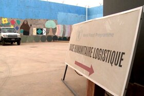 Muro di cinta dipinto, visto dall interno di un cortile, con fuoristrada parcheggiato e cartello base humanitaire logistique