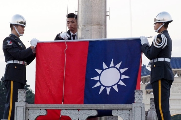 la bandiera di Taiwan mentre viene issata da due militari sulla piazza della libertä a Taipei