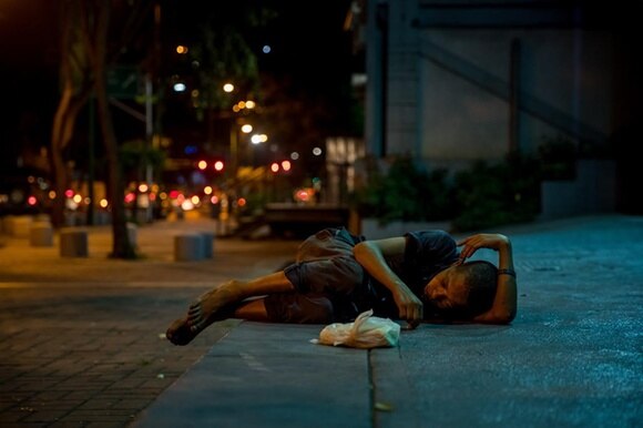 Un bambino dorme sdraiato su un marciapiede, la notte, a Caracas.
