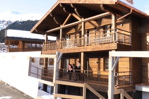 Immagine di un abitazione di montagna costruita in gran parte in legno; potenziali acquirenti la visitano;paesaggio innevato