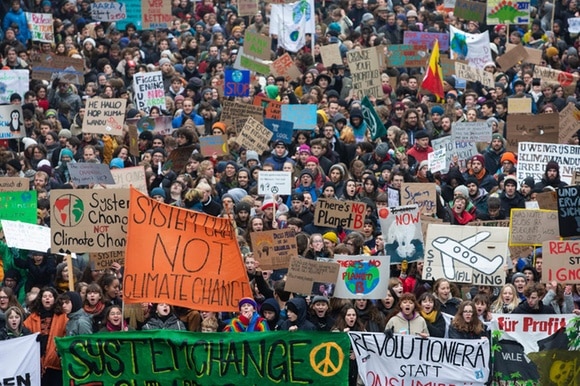 Immagine dall alto di un fitto corteo di giovani con cartelli di tutti i colori riportanti messaggi a favore del clima