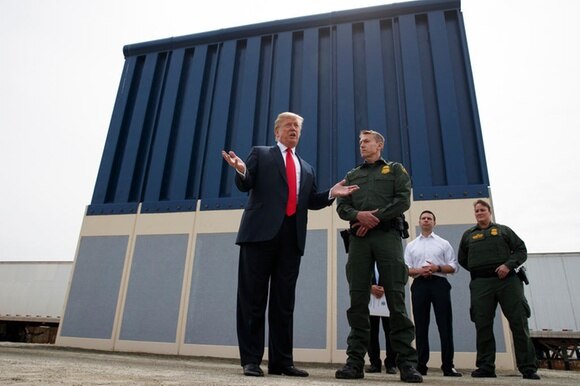 Donald Trump mentre parla con dei giornalisti davanti a un prototipo di muro a San Diego in California