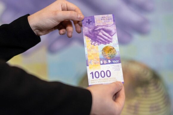 Due mani tengono la nuova banconota da mille franchi