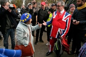 Una signora anziana con cappello raffigurante bandiera europea discute con signore che indossa abito raffigurante l Union Jack