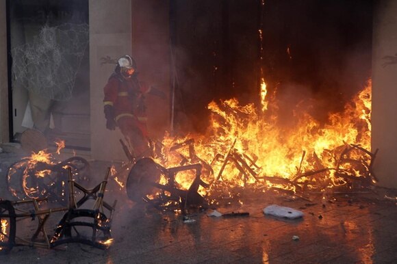Il negozio Longchamps a Parigi che brucia e un pompiere che cerca di fermare il fuoco