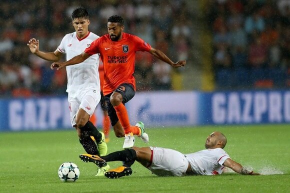 Un giocatore turco tra due difensori del Siviglia nel 2017 durante un turno preliminare di Champions League